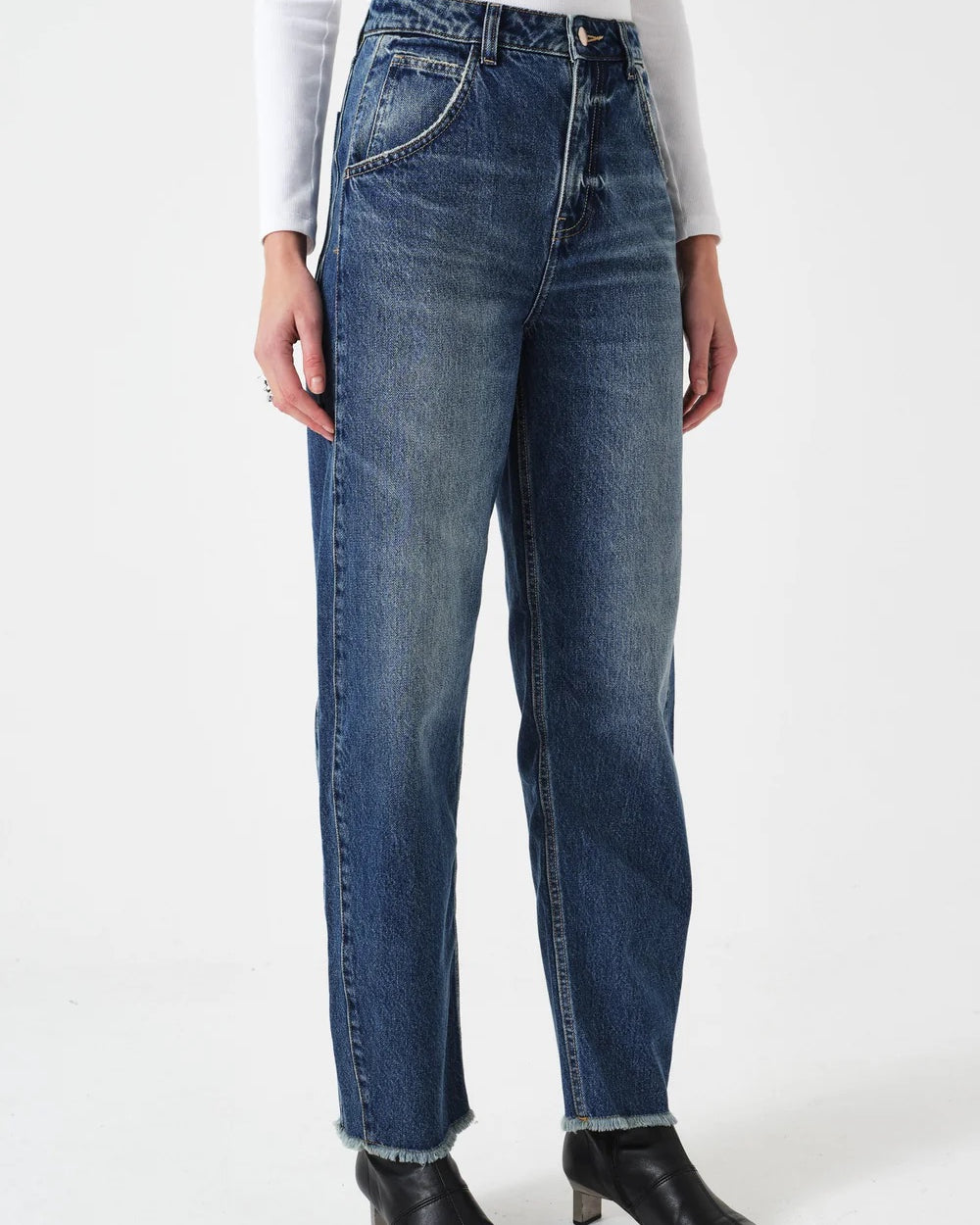 Person wearing blue jeans and black boots on a white background