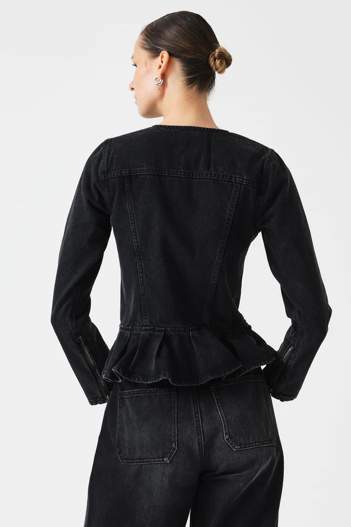 Person wearing a black denim jacket with peplum waist on a white background