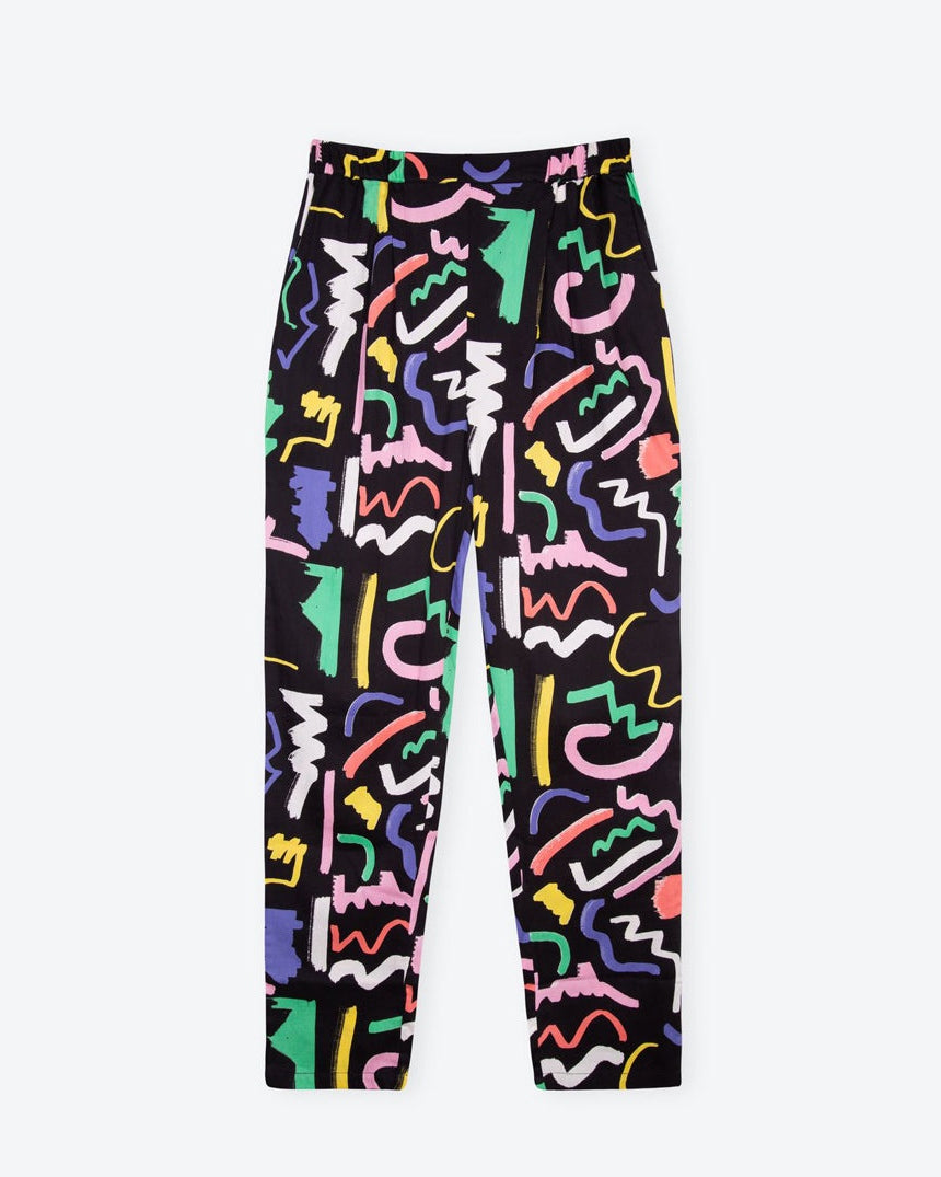 A pair of black trousers with a multicolored scribble print. The trousers have a high-rise fit with an elasticated waistband and side pockets.