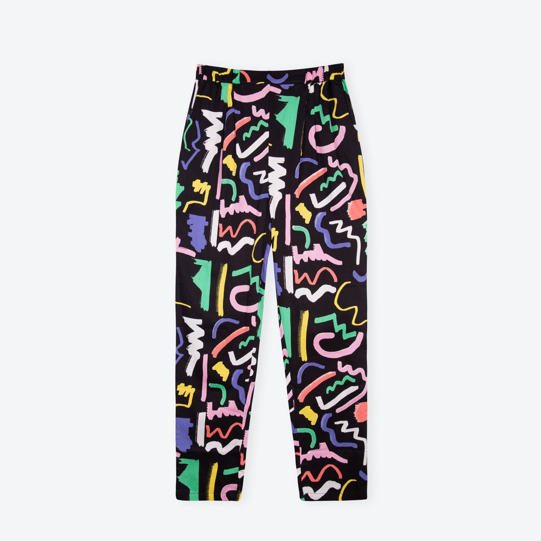 A pair of black trousers with a multicolored scribble print. The trousers have a high-rise fit with an elasticated waistband and side pockets.