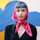 Woman wearing a pink headscarf with a colorful abstract background