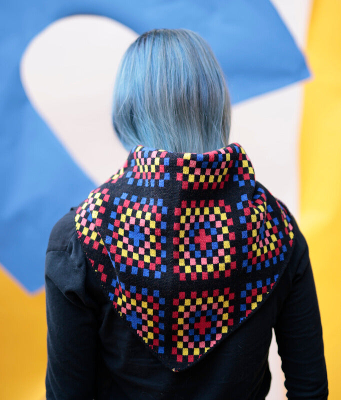 Person wearing a colorful geometric patterned shawl with a multicolored background