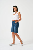 Woman wearing a white tank top and blue denim shorts on a white background