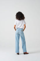 A pair of high-waisted, wide leg jeans with a button-up front in an oceanic blue wash. The jeans are worn with brown ankle boots.