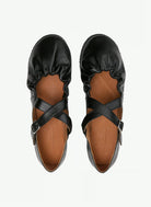 Pair of anguish black cross strap flats on a white background