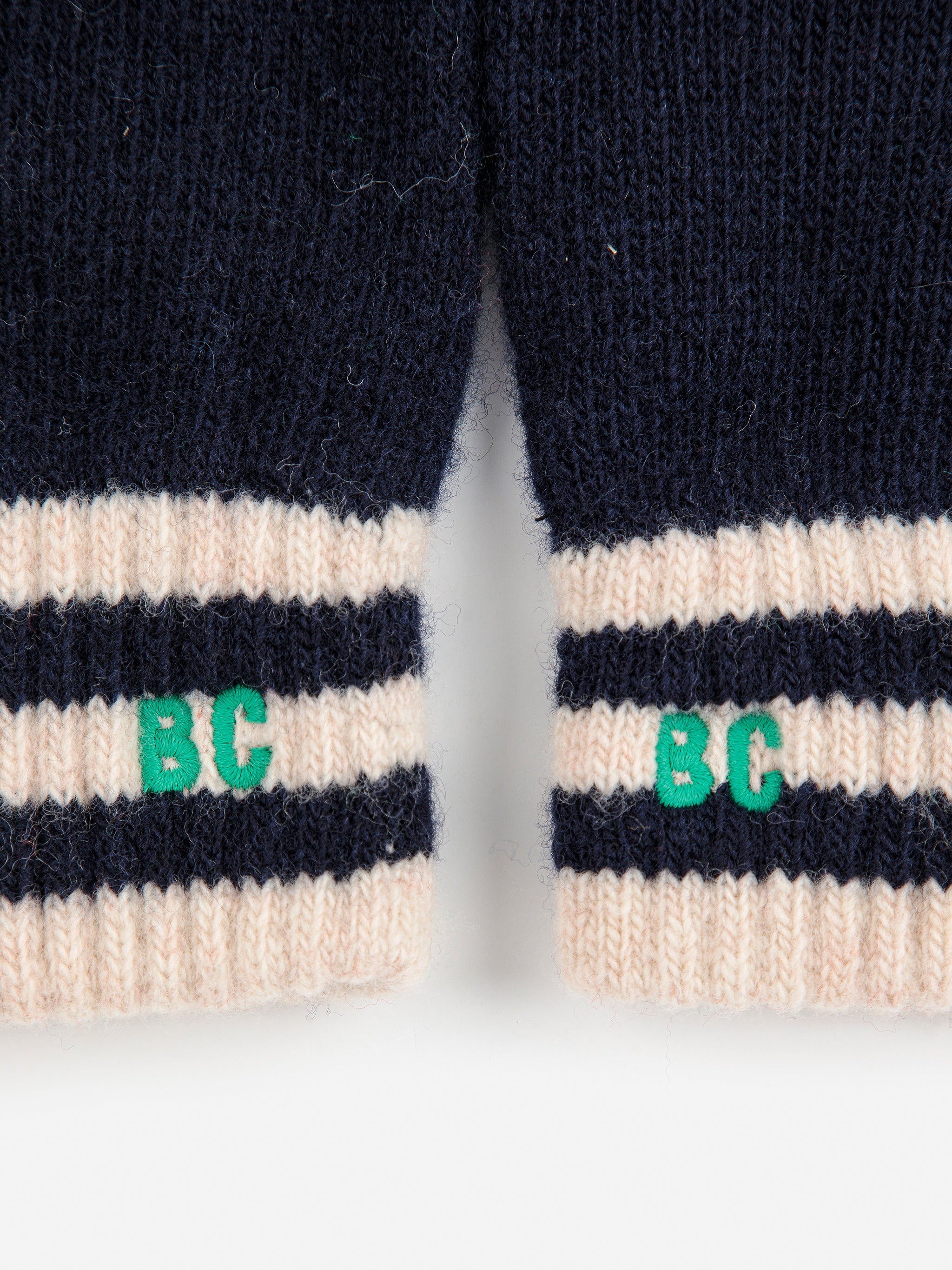 Close-up of navy and beige striped gloves with 'BC' logo on a white background