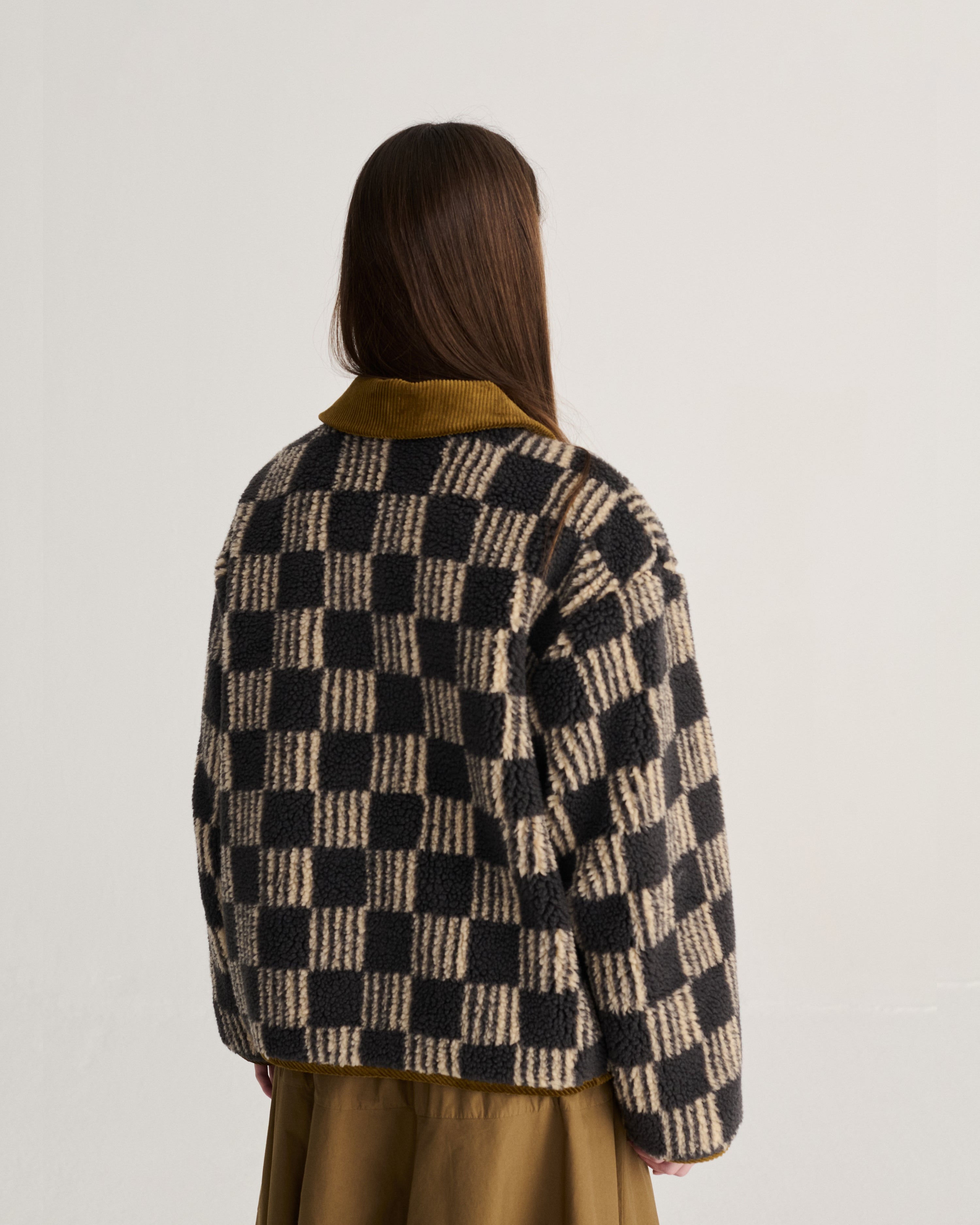 Person wearing a checkered jacket with a plain background