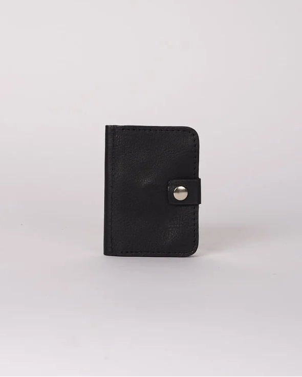 A small black leather card holder or wallet with a snap button closure, standing upright on a light gray background.