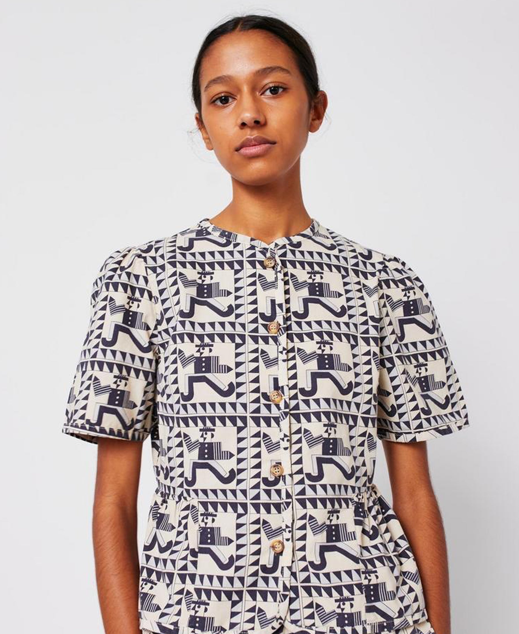 Person wearing a patterned shirt with geometric design on a plain background