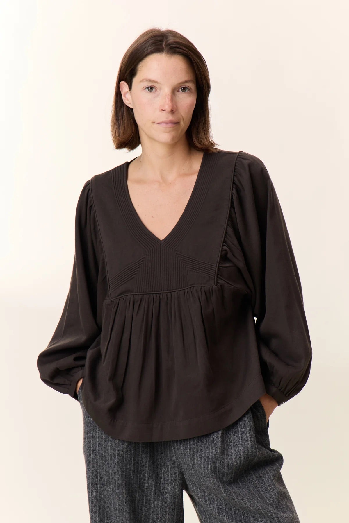 Woman wearing a black blouse with a plain background