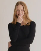 A woman wearing a black long-sleeve top with a relaxed fit and a crew neck.