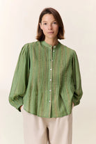 Woman wearing a green striped shirt against a plain background
