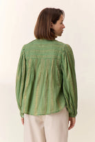 Woman wearing a green patterned blouse against a white background