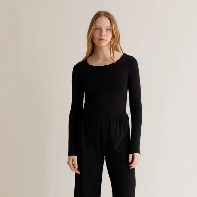 A woman wearing a black long-sleeve top with a relaxed fit and a crew neck.