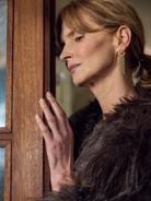 Woman in a fur coat peering through a wooden door