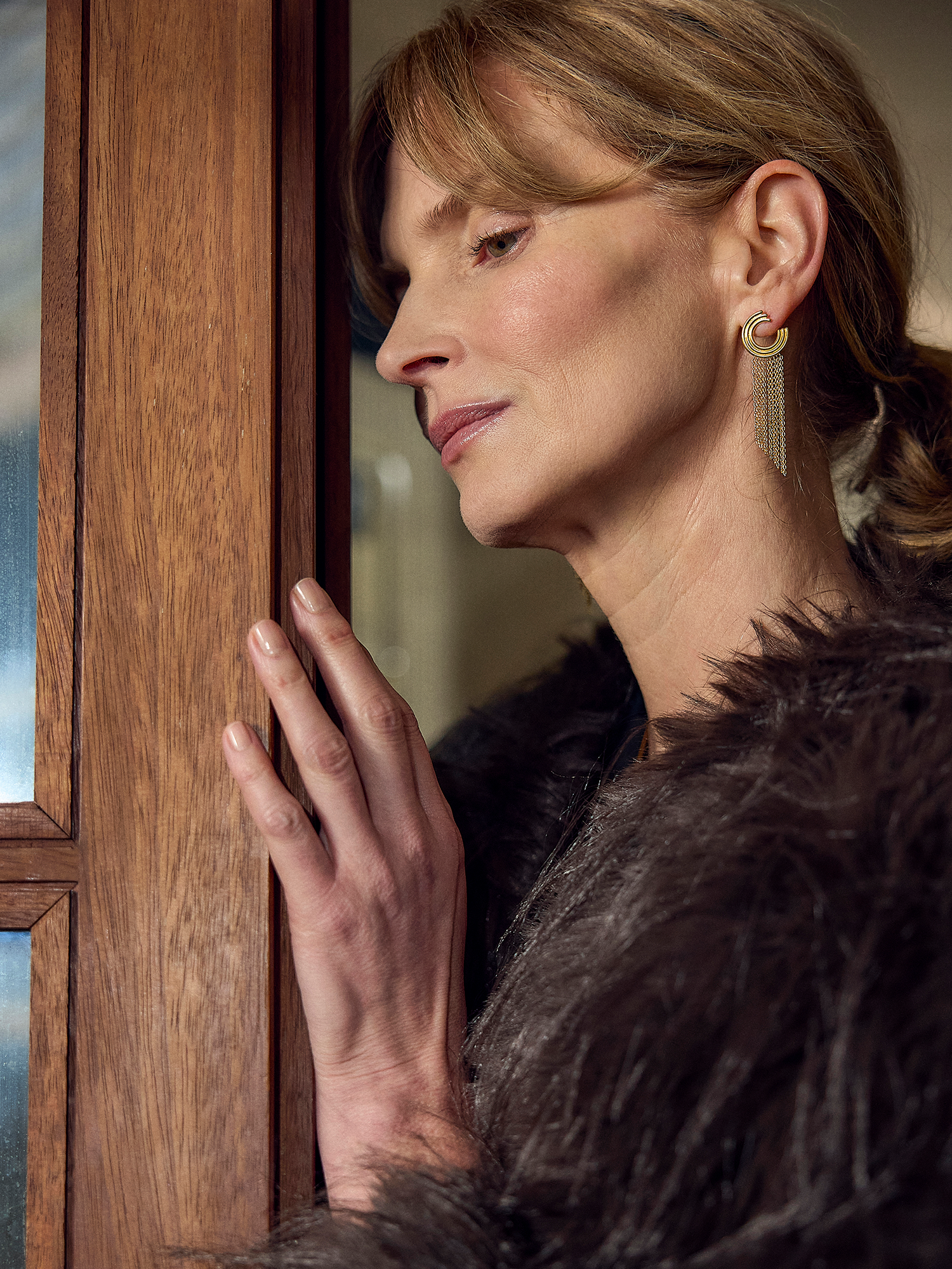 Woman in a fur coat peering through a wooden door