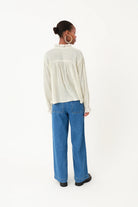 Person wearing a white blouse and blue jeans on a white background