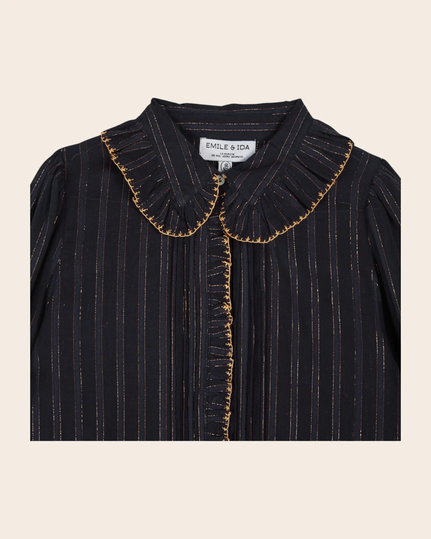 Black pinstripe blouse with gold trim on a beige background