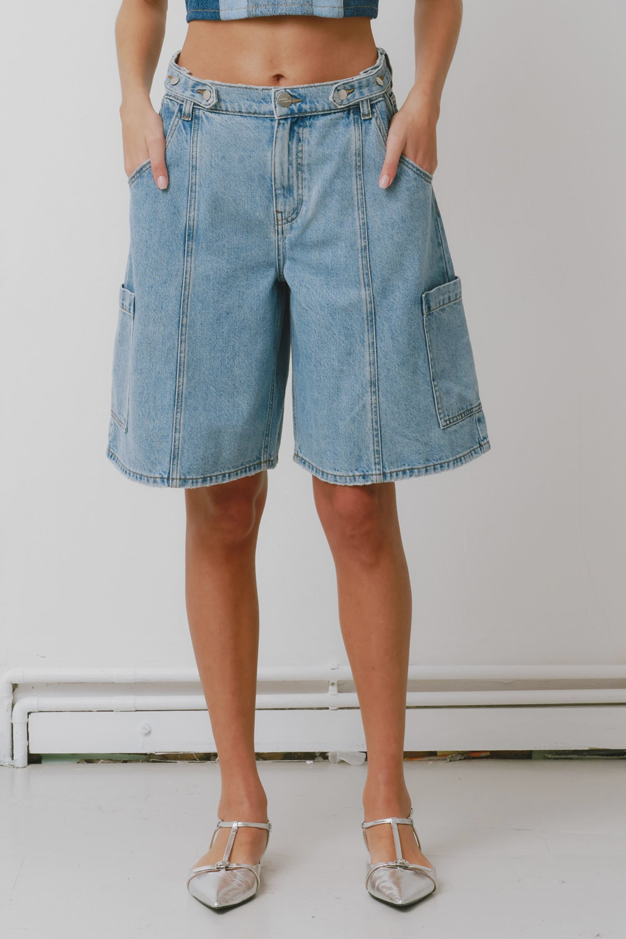 Person wearing blue denim shorts on a plain background