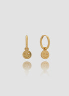 Pair of gold earrings with smiley face charms on a light gray background