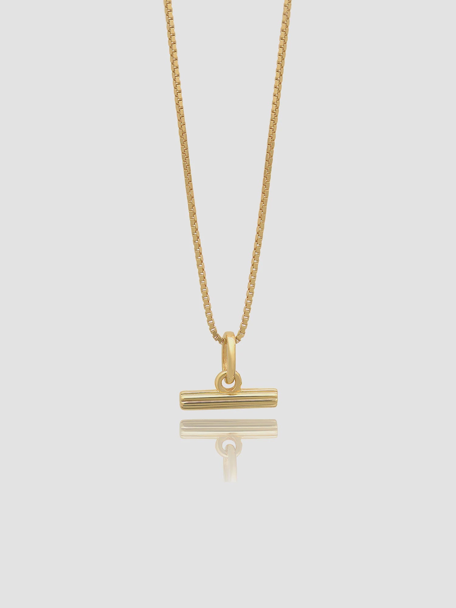 Gold necklace with a unique pendant on a light gray background