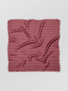 Striped fabric square with frayed edges on a light gray background