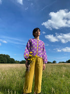 A pair of ochre pleat front trousers with a tab front opening and back jet pockets.