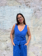 Woman in a blue outfit standing against a textured wall