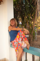 A midi-length orange skirt with a colorful abstract print, featuring side pockets and elasticated back waist.