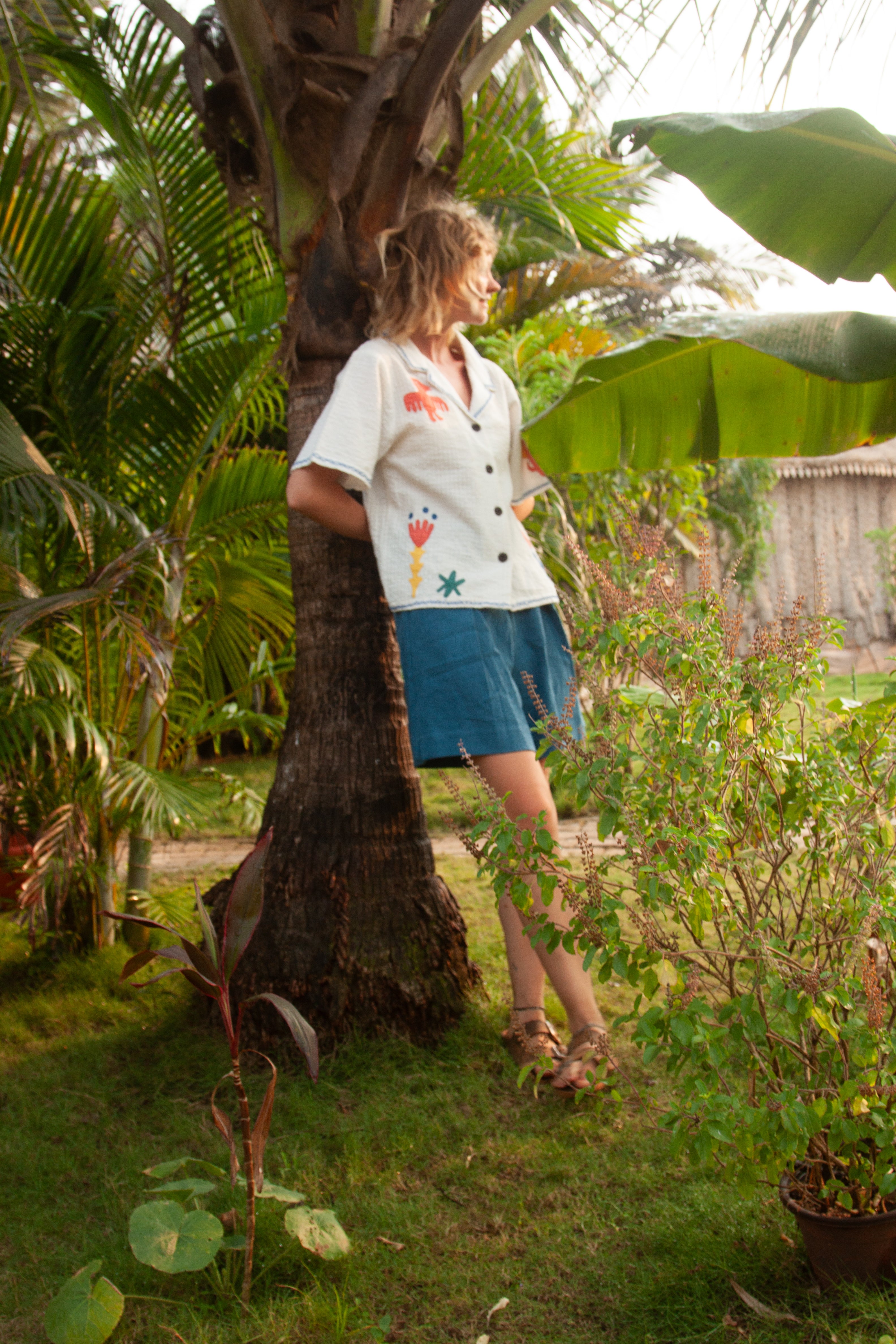Woman in a garden leaning against a tree
