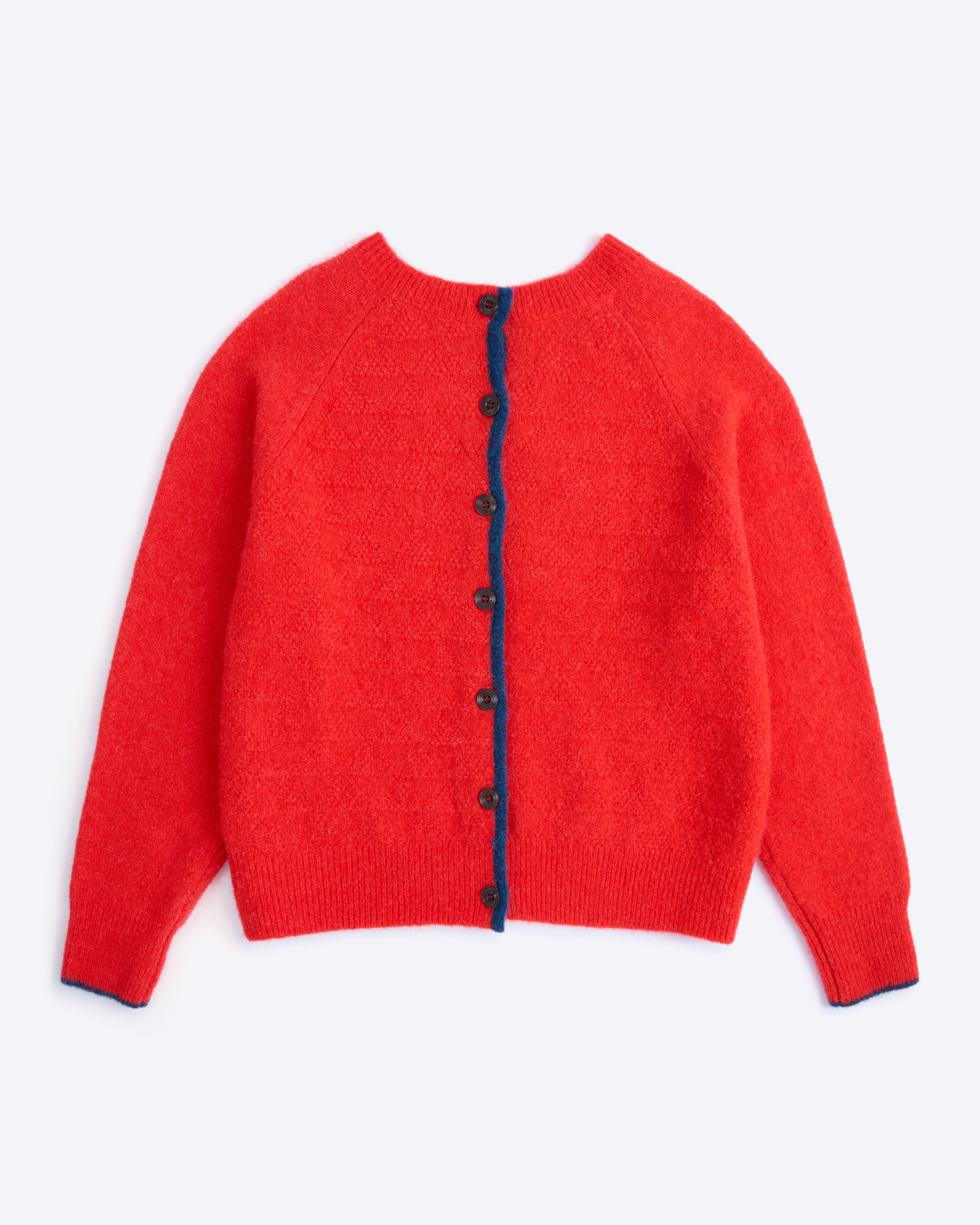 Red cardigan with navy buttons on a white background