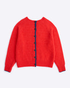 Red cardigan with navy buttons on a white background