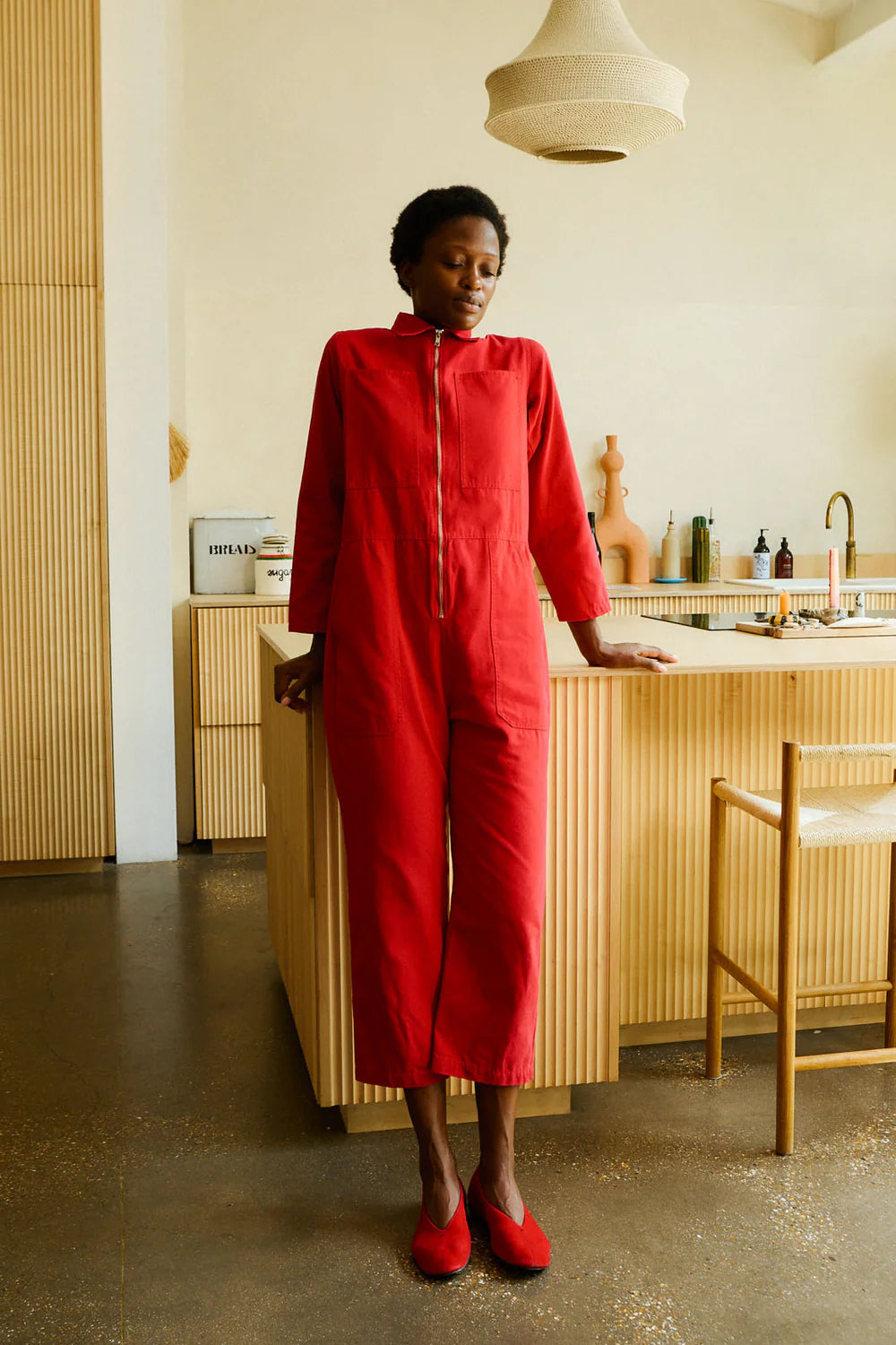 Person wearing a red outfit standing in a modern kitchen.