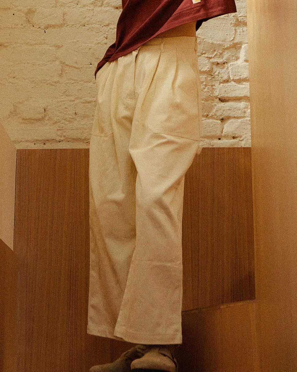 Person wearing beige pants and a maroon top against a stone wall.
