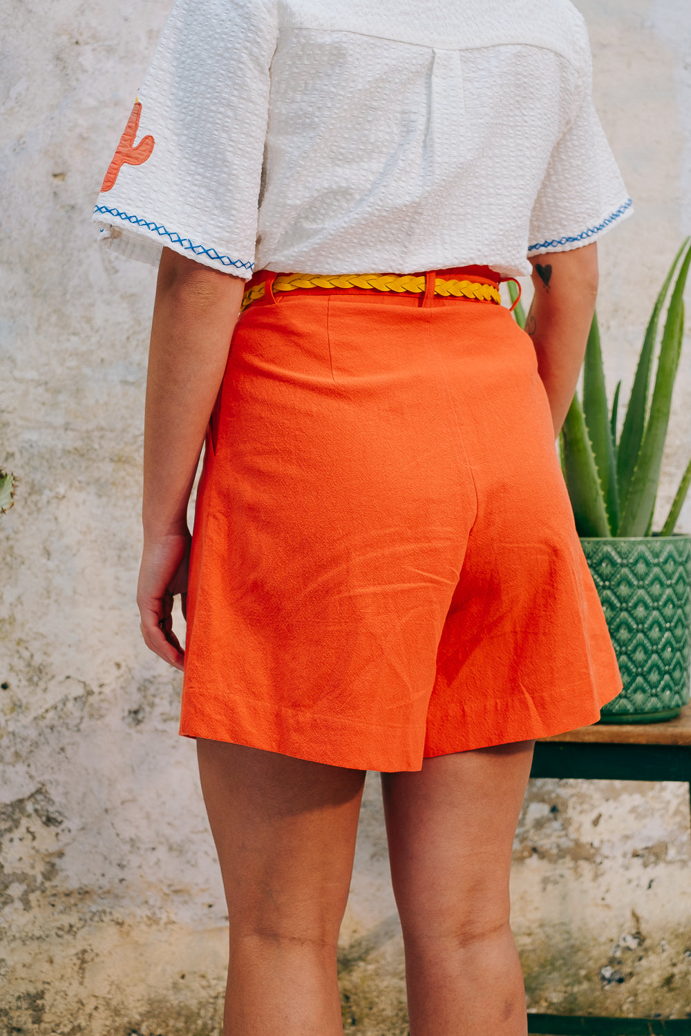 A pair of high-waisted, mid-length, tailored tomato shorts made from a cotton and linen mix.
