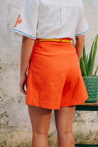 A pair of high-waisted, mid-length, tailored tomato shorts made from a cotton and linen mix.