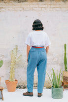A person wearing a white crew neck t-shirt with a hand-crocheted red and yellow cactus and sun motif, paired with a blue skirt and a red belt.
