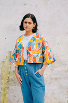 A colorful geometric patterned linen jacket with a V-neckline, elbow length sleeves, and a cropped fit.