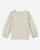 Beige long-sleeve top with black polka dot pattern on a white background