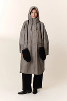Person wearing a long checkered coat with a hood on a white background
