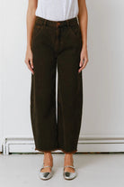 Person wearing dark green wide-leg pants and a white top against a plain background