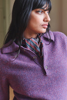 Woman wearing a purple sweater with a patterned scarf, looking to the side.