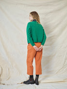 A pair of orange wide leg trousers with pleats and a fixed turn-up hem, made from cotton drill fabric.