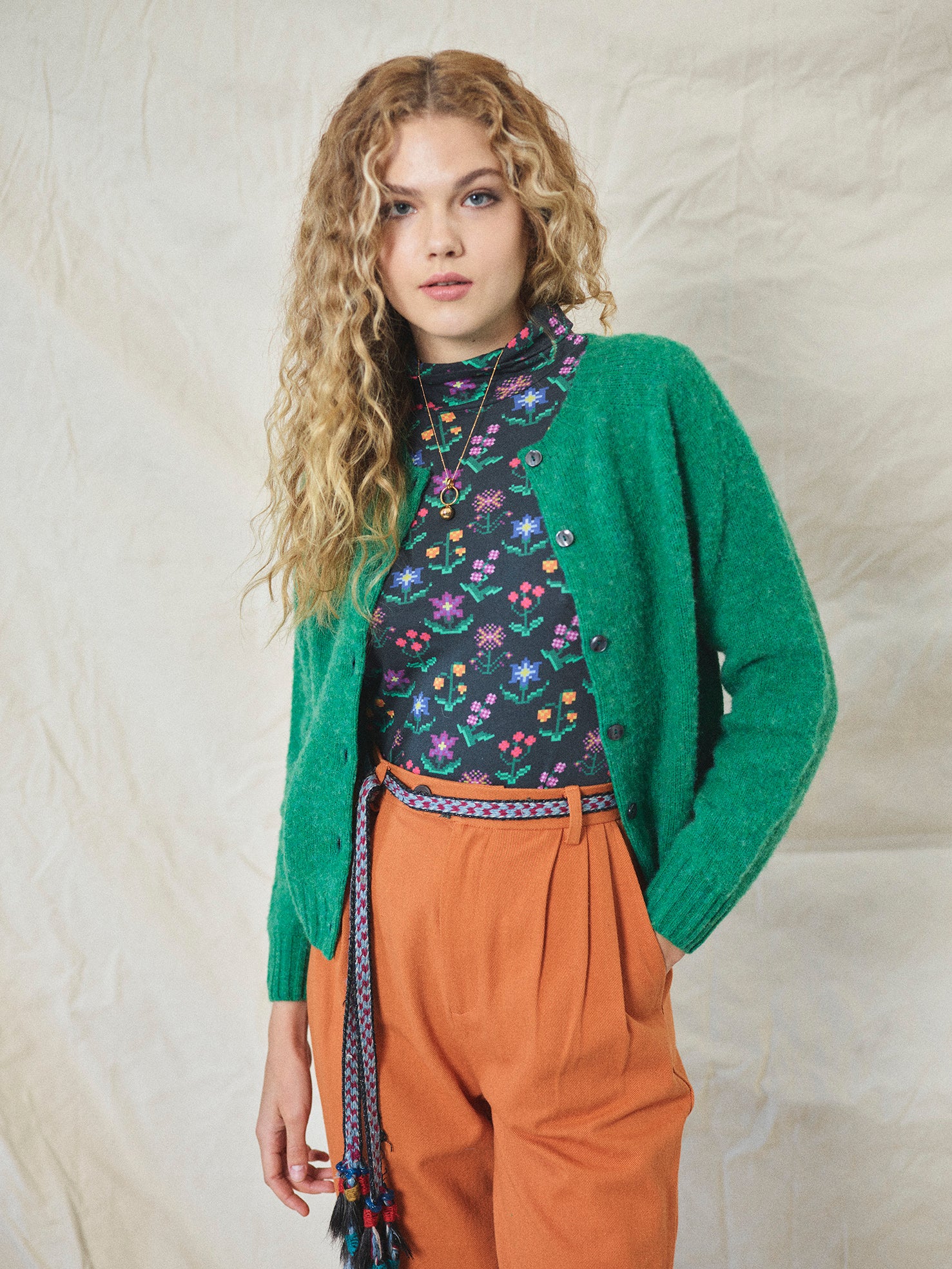 A pair of orange wide leg trousers with pleats and a fixed turn-up hem, made from cotton drill fabric.