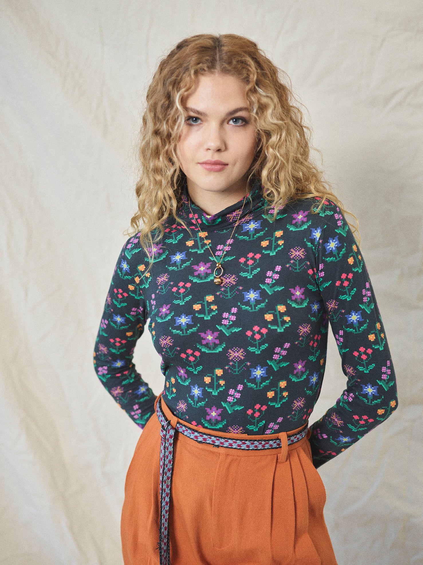 A long sleeve printed roll neck t-shirt with a turtle pattern in multicolor on a black background, made from organic cotton.