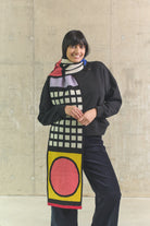 Person wearing a colorful scarf with geometric patterns against a plain background