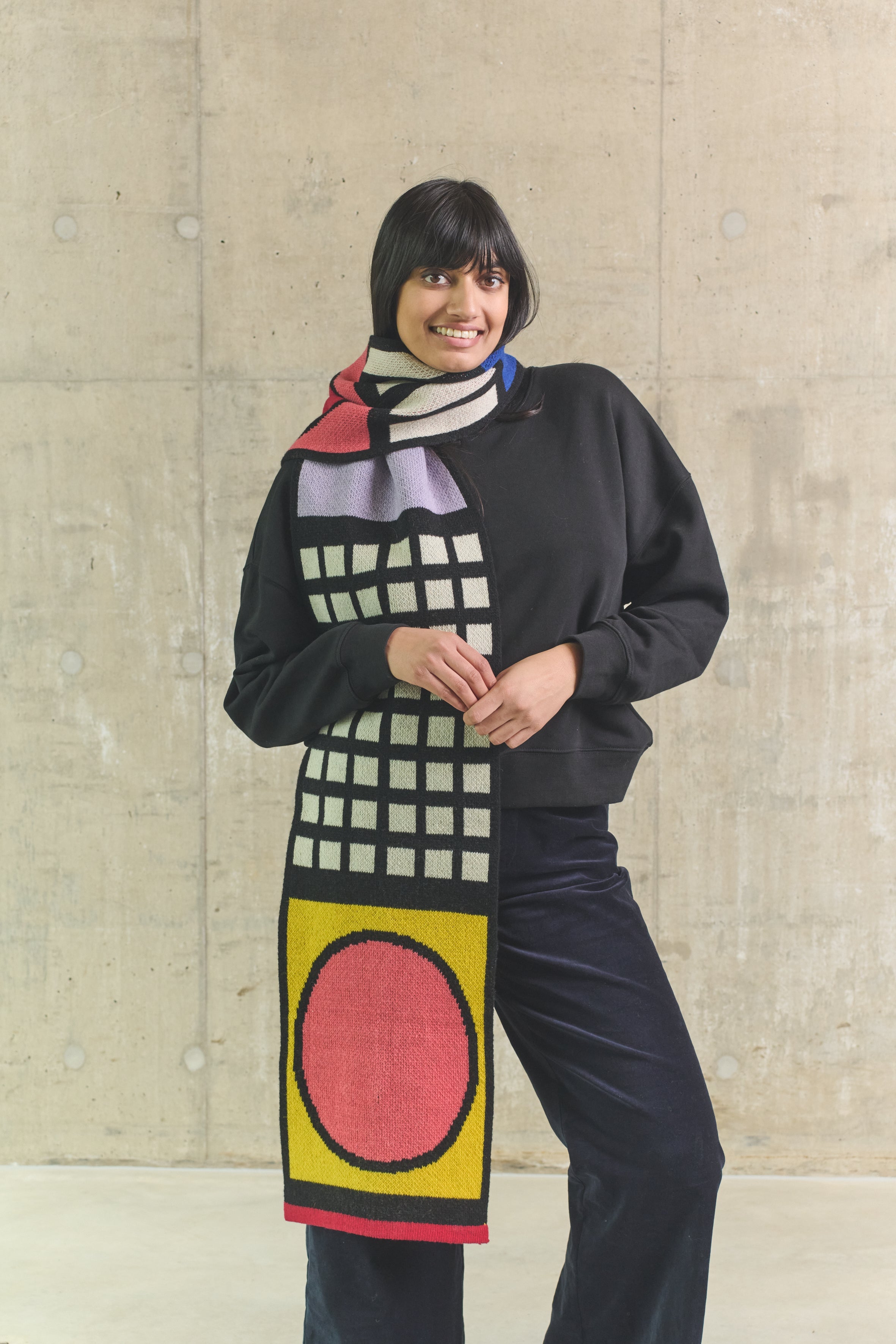 Person wearing a colorful scarf with geometric patterns against a plain background