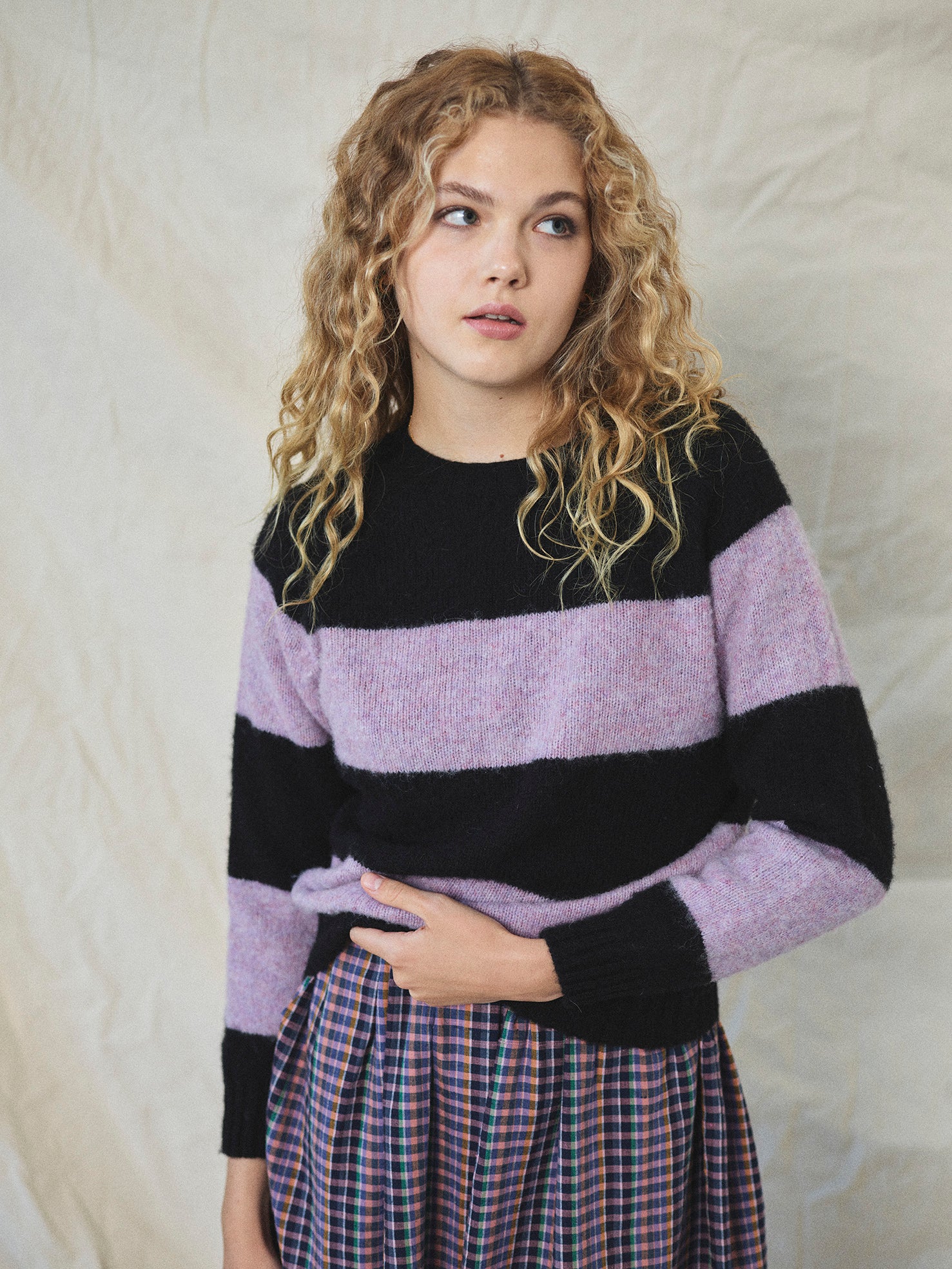A striped Scottish jumper with horizontal black and lilac blocks, featuring a round neckline and ribbed-knit hemline and trim around neck and wrist.