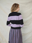 A striped Scottish jumper with horizontal black and lilac blocks, featuring a round neckline and ribbed-knit hemline and trim around neck and wrist.