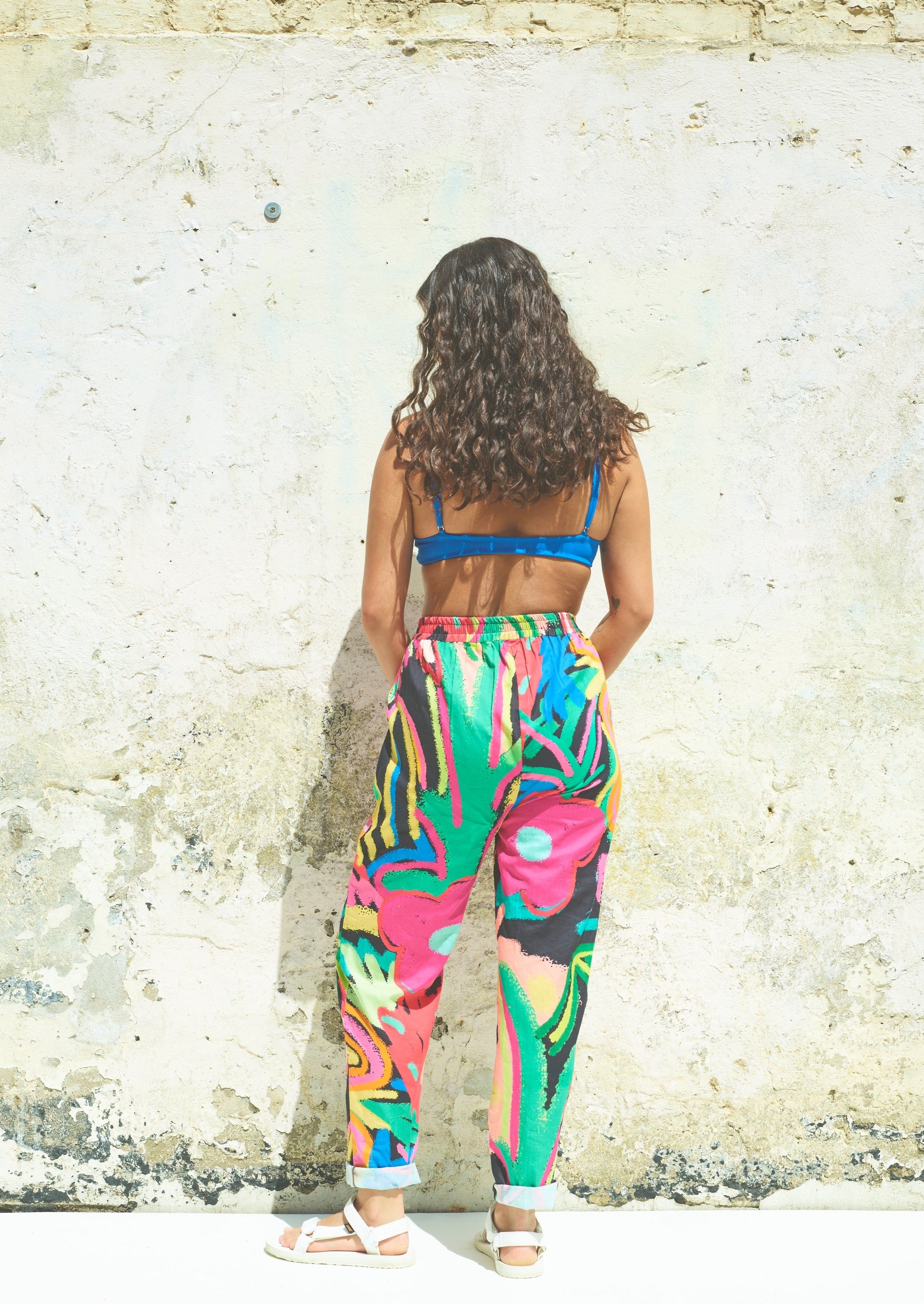 A pair of Miss Pompom Jungle Holiday Trousers with a vibrant hand-drawn tropical print in bright colors.